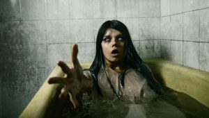 Scary girl in bath stretching her hand to camera, Halloween theme
